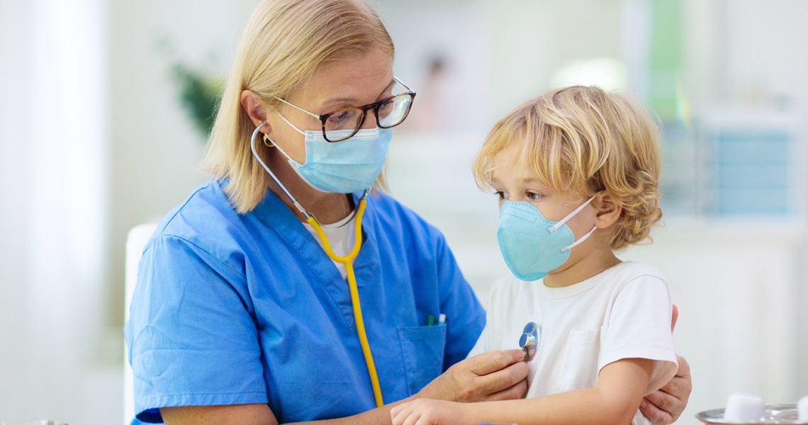 Pediatrician doctor examining sick child in face mask